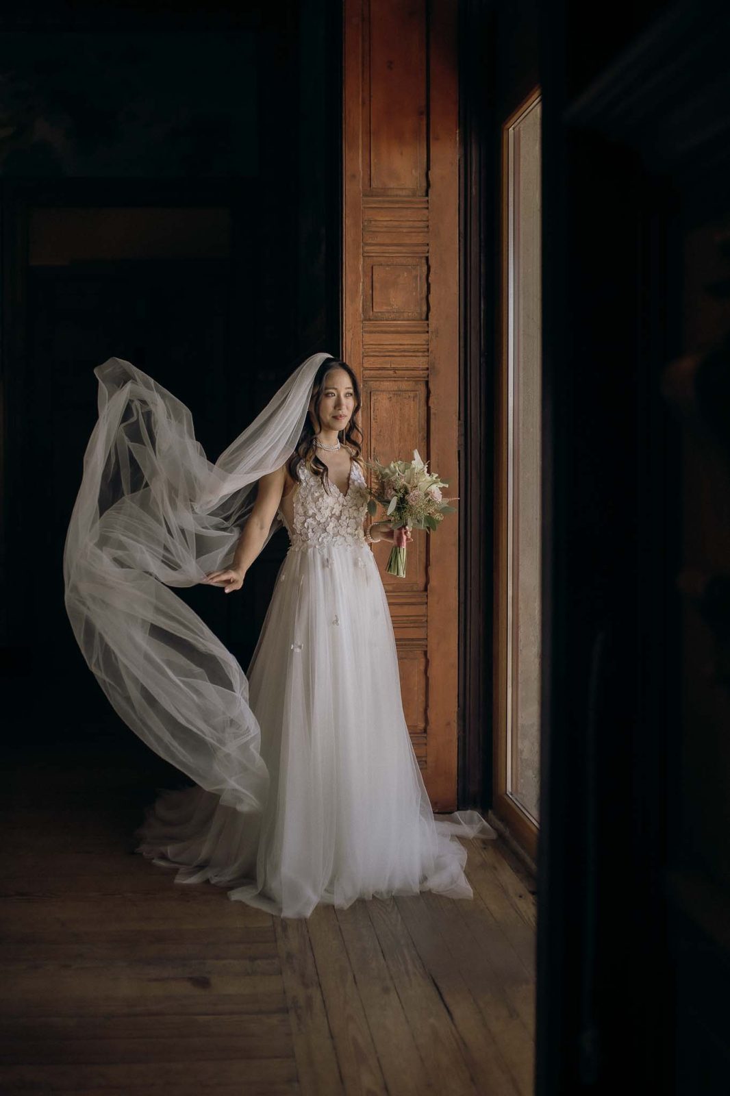 dark and moody portrait of bride waving her veil